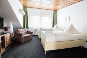 a hotel room with two beds and a chair at Hotel Zum Eisenhammer in Oberhausen