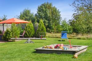 a sandbox in a yard with a chair and an umbrella at Hof Lueck in Esens
