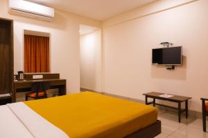 a hotel room with a bed and a desk and a tv at Hotel Dreamland in Pune
