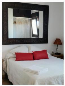 a white bed with two red pillows and a mirror at ZARATUSTRA. Rodalquilar CENTRO. GRAN terra. WIFI in Rodalquilar