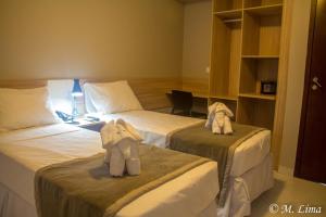 Dos camas en una habitación de hotel con animales de peluche. en Hotel Enseada Aeroporto en Recife