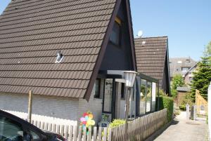 een huis met een zwart dak en een hek bij Ferienhaus Breithaupt in Cuxhaven
