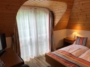 a bedroom with a large window in a wooden house at Zöldtető Panzió in Balatonfüred