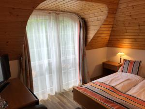 バラトンフレドにあるZöldtető Panzióの木造家屋内の大きな窓付きのベッドルーム