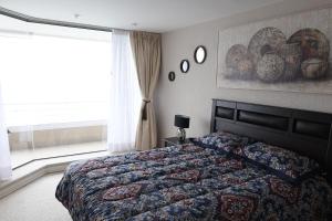 a bedroom with a bed and a window with plates on the wall at Condominio San Alfonso Del Mar - Vista Inmejorable in Algarrobo