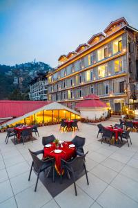 a patio with tables and chairs and a building at Snow Valley Resorts Shimla in Shimla