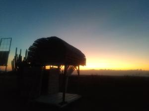 a silhouette of a hut in a field at sunset at biohotel tatacoa Qji in Villavieja