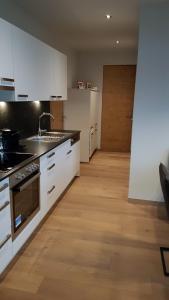 a kitchen with white appliances and a wooden floor at Appartement Mountainview in Saalbach Hinterglemm