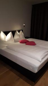 a large white bed with red pillows on it at Appartement Mountainview in Saalbach Hinterglemm