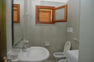 bagno bianco con lavandino e servizi igienici di Residence della Torre Isola Rossa a Isola Rossa