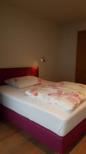 ein Bett mit einer weißen Matratze mit Blumen darauf in der Unterkunft Appartement Mountainview in Saalbach-Hinterglemm