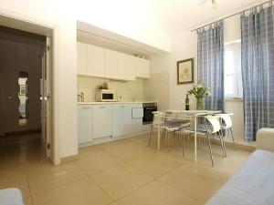 a kitchen with white cabinets and a table and chairs at Apartmani Val in Pula