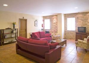 a living room with red couches and a tv at La Piedra del Mediodía in Cirat