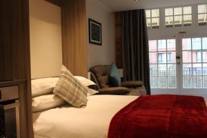 Habitación de hotel con cama, silla y ventana en Waters Edge at Cocoa Suites, en York