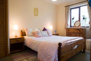 Un dormitorio con una cama grande y una ventana en Nethercote Cottage, Seven Springs Cottages, en Cheltenham