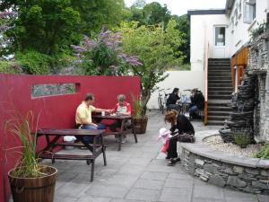 a group of people sitting at tables in a garden at Killarney Railway Hostel in Killarney