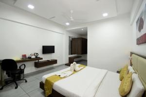 a bedroom with a bed and a desk and a television at CRIMSON PARK Shripriya-Nathdwara in Nāthdwāra