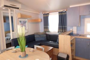 uma pequena sala de estar com um sofá azul e uma mesa em Camping Clau Mar Jo em Bormes-les-Mimosas