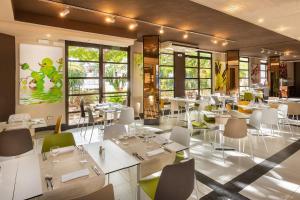 un restaurante con mesas y sillas blancas y ventanas en Aguamar Apartamentos, Los Cristianos Downtown, en Los Cristianos