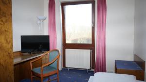a room with a desk with a television and a window at Entrée Hotel Glinde in Hamburg