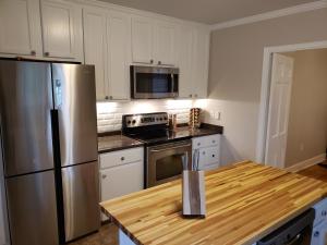 una cucina con frigorifero in acciaio inossidabile e tavolo in legno di Heritage Inn BNB a Holly Springs