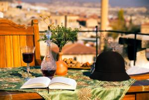 een tafel met een hoed en een open boek erop bij Cappadocia Perimasali Cave Hotel in Urgup