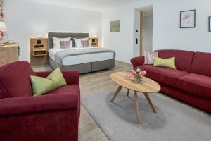 ein Wohnzimmer mit 2 Sofas und einem Bett in der Unterkunft Hotel Obermaier in München
