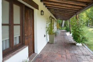 une terrasse couverte d'une maison avec une porte en bois et des plantes en pot dans l'établissement Postales Hotel Boutique Valle De Uco, à Colonia Las Rosas