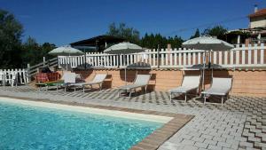 a group of chairs and umbrellas next to a pool at Agriturismo Terre D'Ulivi in Moscufo