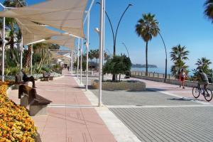 a person riding a bike on a sidewalk next to the ocean at CASA LUCA in Estepona