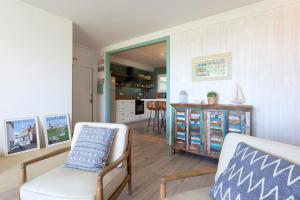 salon z 2 krzesłami i kuchnią w obiekcie Gavamar Castelldefels Beachfront Apartment- Direct access to the beach w mieście Gavà