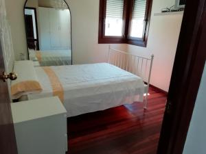 a bedroom with a white bed and a mirror at Casa Airiños do monte in Cangas de Morrazo