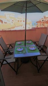 una mesa con platos y una sombrilla en el balcón en Ático en La Noria, piscina privada en primera línea de playa., en San Luis de Sabinillas