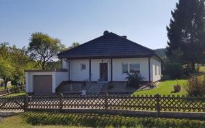 a small white house with a fence in front of it at Ferienhaus Gemütlichkeit in Mehlmeisel