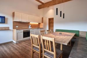 Il comprend une cuisine et une salle à manger avec une table et des chaises en bois. dans l'établissement Appartment Ransburggut, à Flachau