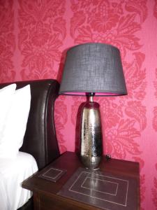 a lamp sitting on a table next to a bed at The Cross Guest House in Mablethorpe