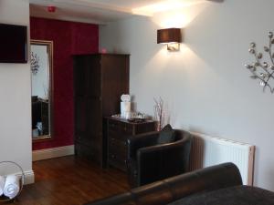 ein Wohnzimmer mit einem Ledersessel und einer Kommode in der Unterkunft The Cross Guest House in Mablethorpe