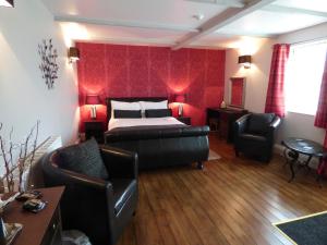 a bedroom with a bed and a couch and chairs at The Cross Guest House in Mablethorpe