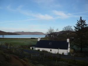 a white house with a fence and a lake at Glas Bheinn Cottage in Luib