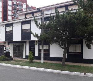 a white and black building with a tree in front of it at HOTEL SAN JORGE in San Clemente