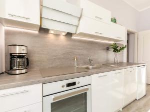 a kitchen with white cabinets and a sink at VacationClub – Poleska 4C Apartament 7 in Kołobrzeg