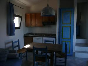 a kitchen with a table and chairs and a blue door at Cormorani Alti in Baja Sardinia