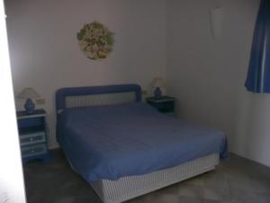 a bedroom with a blue bed and two night stands at Cormorani Alti in Baja Sardinia