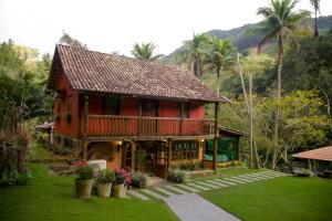 een rood huis met een balkon en een tuin bij Pousada Vila do Loro in Domingos Martins