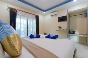 a bedroom with a large white bed with blue pillows at The Sun Long Beach Resort in Ko Lanta