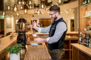 Ein Mann steht an einer Bar und macht einen Drink. in der Unterkunft Hotel Obermaier in München