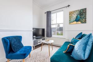 ein Wohnzimmer mit einem blauen Sofa und einem TV in der Unterkunft Modern, Romantic Apartment in York - Pass the Keys in York