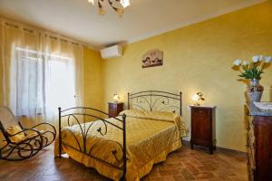 um quarto com uma cama, uma cadeira e uma janela em Agriturismo MonteCrespini em Saturnia