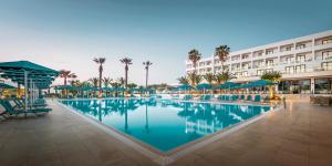 einen Pool in einem Resort mit Palmen und einem Gebäude in der Unterkunft Mitsis Faliraki in Faliraki