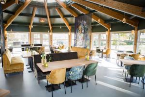 a dining room with tables and chairs and windows at Hotel Bornholm in West-Terschelling